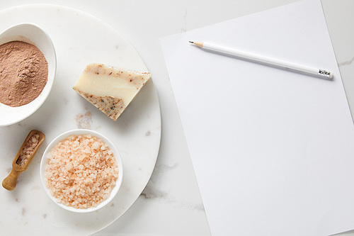 top view of clay powder, soap and 씨솔트 on marble table near white paper and pencil