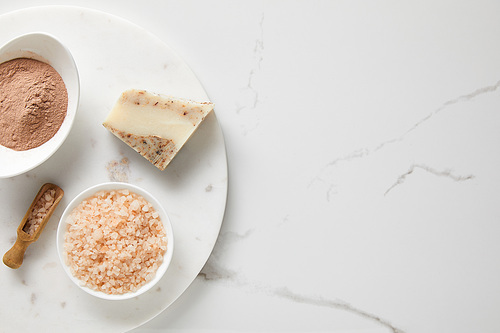 top view of clay powder and 씨솔트 in bowls on marble table near wooden spatula and soap