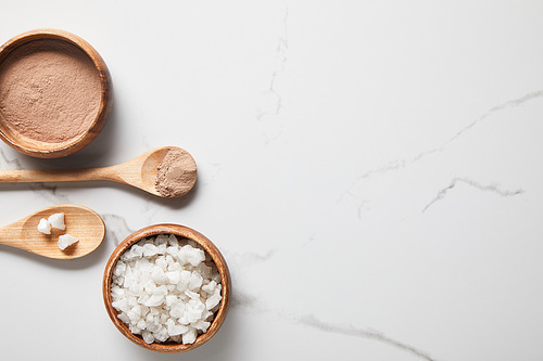 top view of clay powder and 씨솔트 in wooden bowls and spoons on marble table