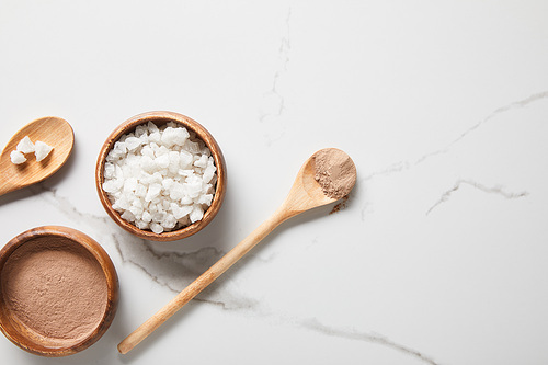 top view of clay powder and 씨솔트 in bowls on marble table near wooden spoons