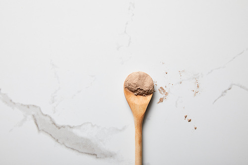 top view of clay powder in wooden spoon on marble table