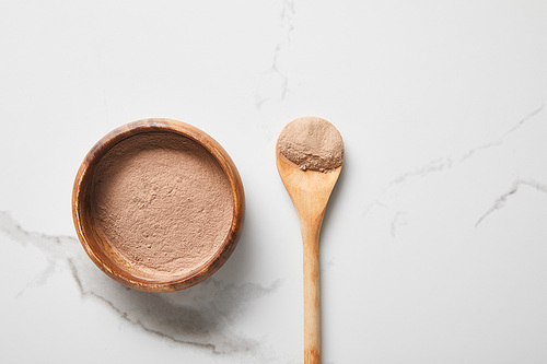 top view of clay powder in bowl and spoon on marble table