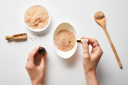 cropped view of woman preparing organic cosmetics from ingredients on white background