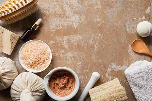 top view of organic cosmetics and beauty supplies on textured weathered beige surface