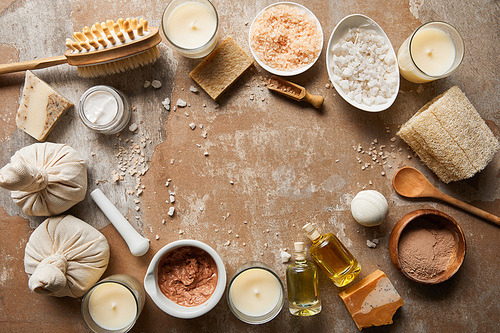 top view of natural cosmetics and beauty supplies near decorative candles on textured weathered beige surface