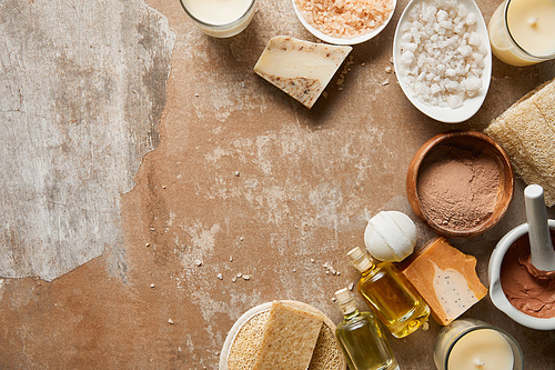 top view of natural cosmetic ingredients and candles on textured weathered beige surface