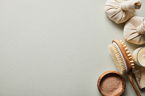 top view of clay powder in wooden bowl near massage brush, candle on white background