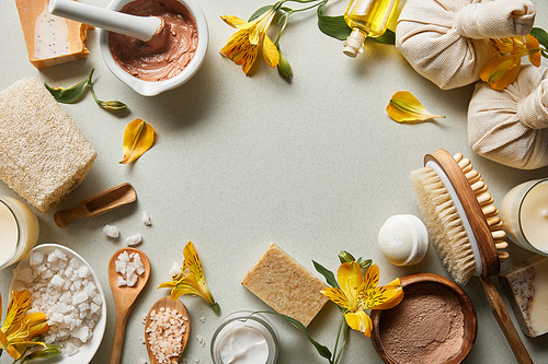 top view of organic cosmetics and beauty supplies on white background with candles and yellow flowers