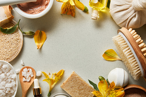 top view of organic cosmetics and beauty supplies on white background with yellow flowers and copy space