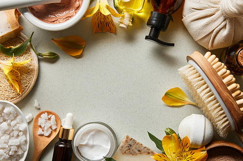 top view of organic cosmetics and beauty supplies on white background with yellow petals