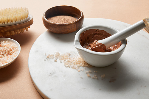 clay and 씨솔트 in bowls on marble circle near wooden massage brush