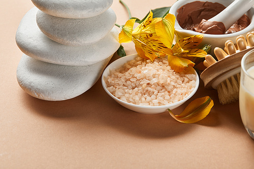 close up view of 씨솔트, clay, stones, massage brush and yellow flowers on beige surface