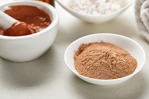 close up view of brown clay and clay powder in white bowls