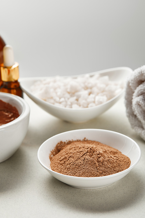 selective focus of clay powder and 씨솔트 in bowls isolated on grey