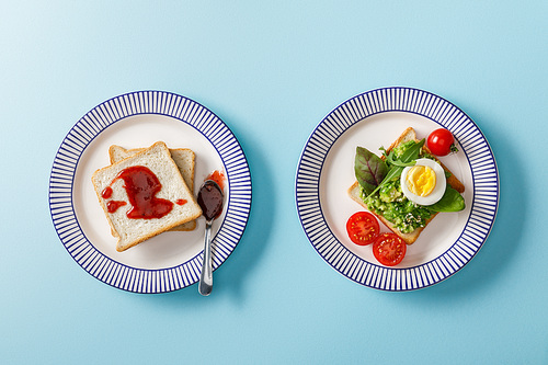 top view of served breakfast, toasts with guacamole and jam on blue background