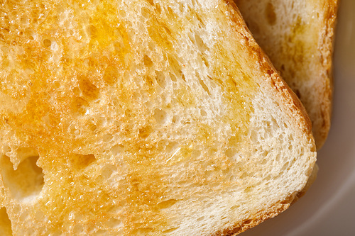 close up view of toasts with honey on white plate