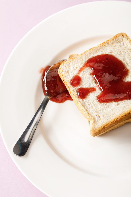 close up view of toasts and spoon with jam on white plate isolated on violet