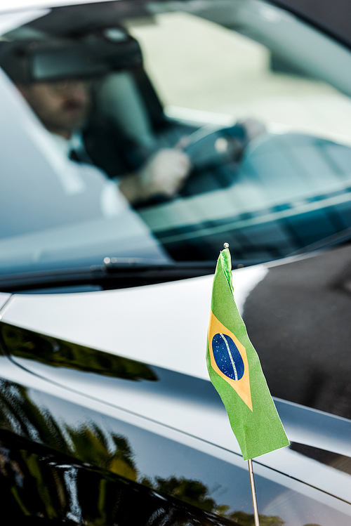 selective focus of brazilian flag near man in modern car