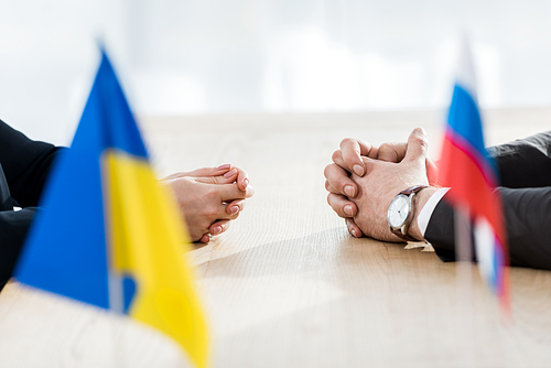 selective focus of ambassadors with clenched hands near ukrainian and russian flags