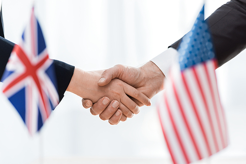 selective focus of diplomats shaking hands near flags of usa and united kingdom