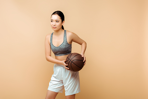 Asian sportswoman with ball isolated on beige