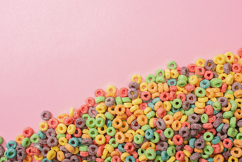 top view of bright multicolored breakfast cereal on pink background