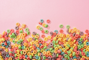top view of bright multicolored breakfast cereal on pink background