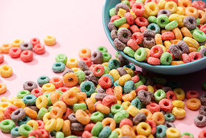 bright colorful breakfast cereal scattered from bowl on pink background