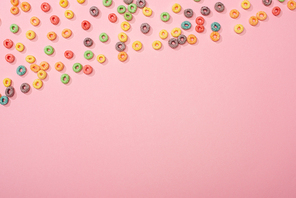 top view of bright colorful breakfast cereal scattered on pink background