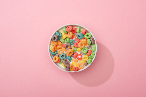 top view of bright colorful breakfast cereal in bowl on pink background