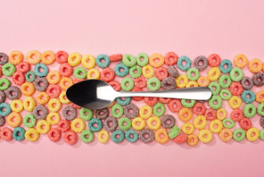 top view of bright colorful breakfast cereal and spoon on pink background