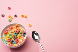 bright colorful breakfast cereal with milk in bowl with spoon on pink background