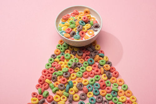 bright colorful breakfast cereal with milk in bowl and on pink background