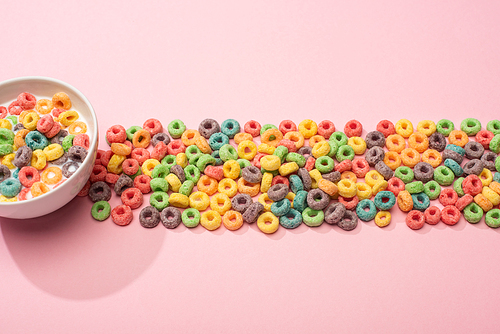 bright colorful breakfast cereal with milk in bowl and on pink background