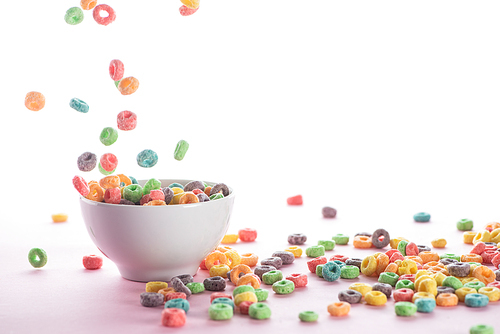 bright multicolored breakfast cereal falling in bowl on white background
