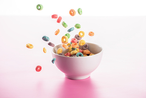 bright multicolored breakfast cereal in bowl on pink background