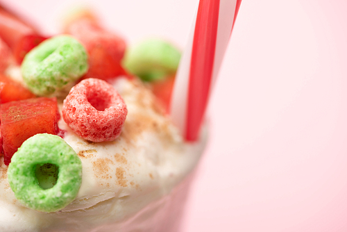 selective focus of strawberry milkshake with ice cream, colorful candies and  tube on pink background