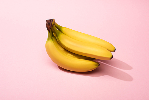 Ripe yellow bananas on pink background