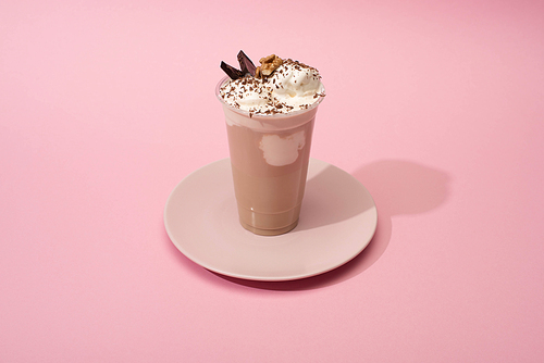 High angle view of disposable cup of chocolate milkshake on plate on pink background