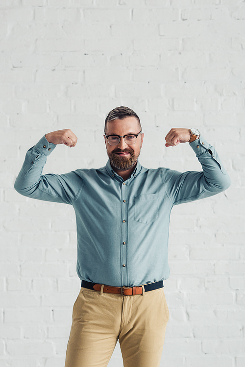 handsome and smiling businessman in shirt showing gesture in office