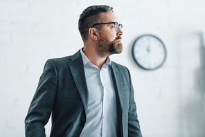 handsome businessman in formal wear and glasses looking away