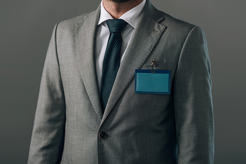 Cropped view of man in suit with badge isolated on grey