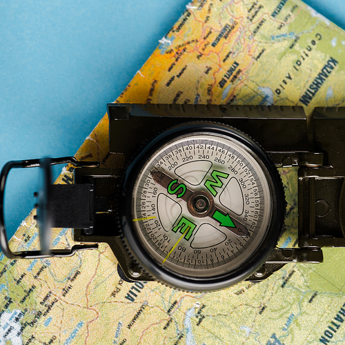 close up of black compass near map on blue