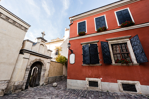 red old house with shutters on windows near arch with door in lviv, ukraine
