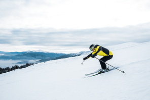 athletic man in helmet and goggles skiing on slope