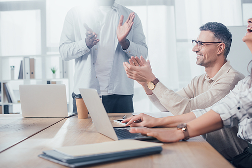 cropped view of smiling multicultural colleagues clapping during meeting in creative agency