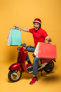 happy delivery man in red uniform with shopping bags on scooter on yellow background