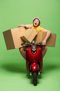 delivery man in yellow uniform with open mouth on scooter with boxes on green
