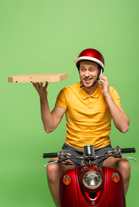 smiling delivery man in yellow uniform on scooter with pizza talking on smartphone isolated on green
