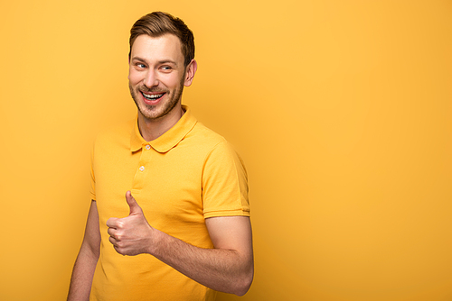 happy handsome man in yellow outfit showing thumb up on yellow background